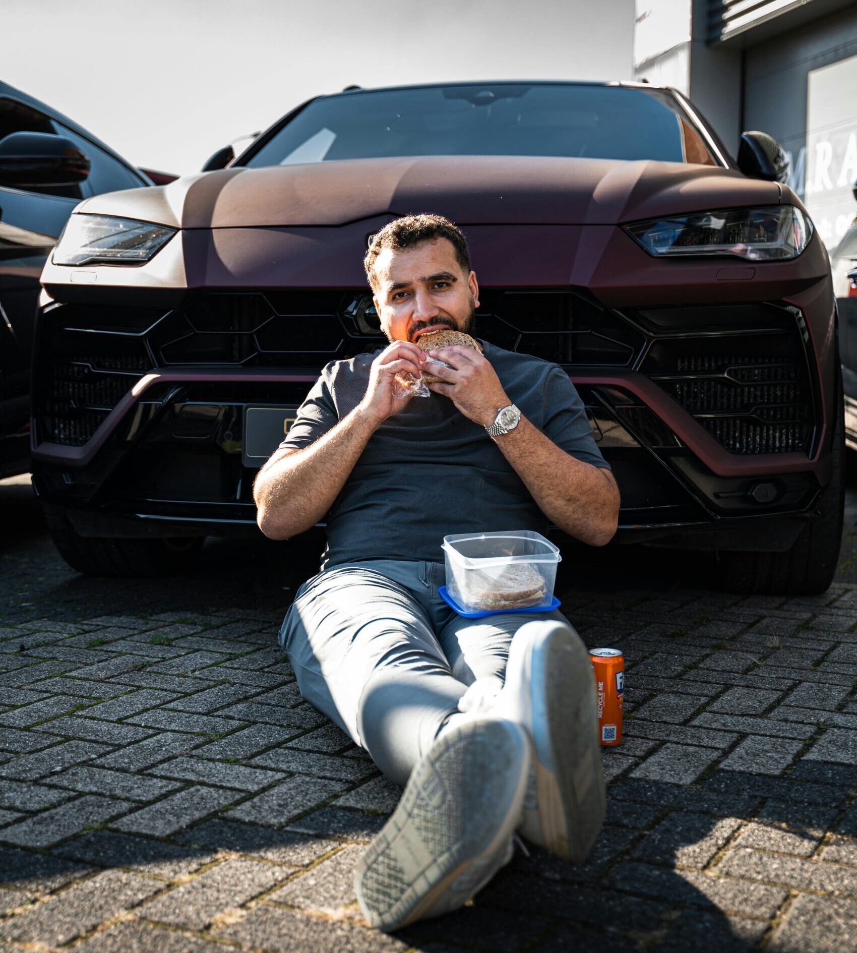 mann-sitzt-essend-vor-einem-auto