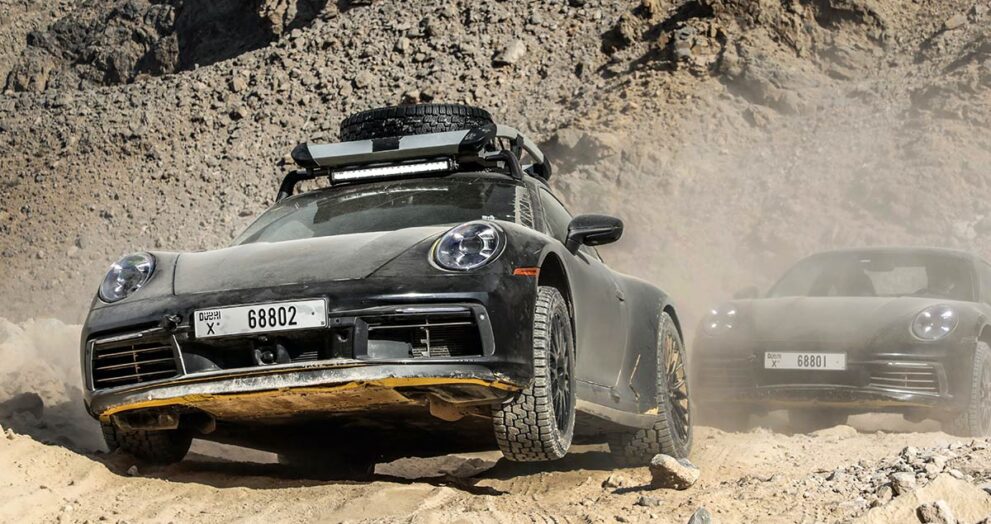 zwei-porsche-911-dakar-fahren-durch-wuestenlandschaft